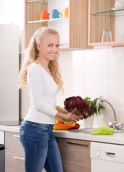 Menina lavar legumes na cozinha — Fotografia de Stock