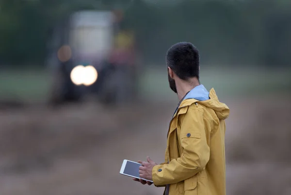 Bonde innehav tablett med traktor bakom — Stockfoto
