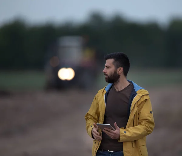 Farmer holding tablet con trattore dietro — Foto Stock