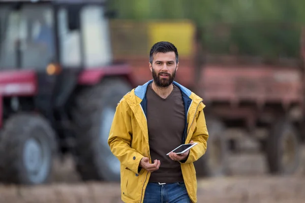 Bonde innehav tablett med traktor bakom — Stockfoto