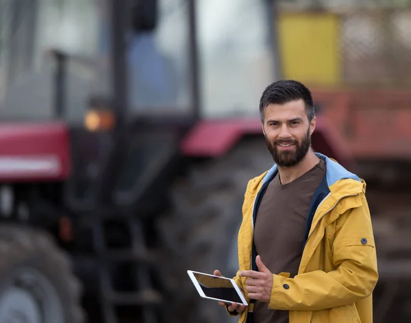 Tabletka gospodarstwie rolnik z ciągnika za — Zdjęcie stockowe