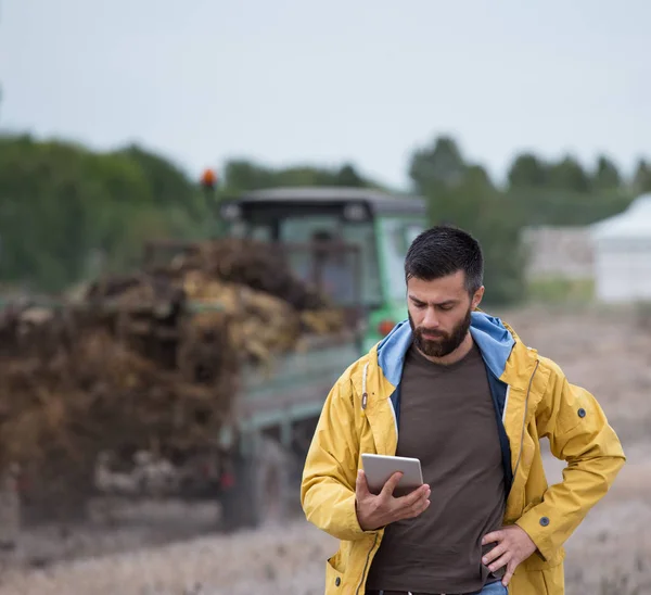 Farmer holding tablet with tractor behind — Stock Photo, Image