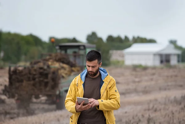 Farmer segurando tablet com trator atrás — Fotografia de Stock