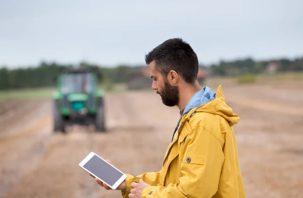 Bonde innehav tablett med traktor bakom — Stockfoto