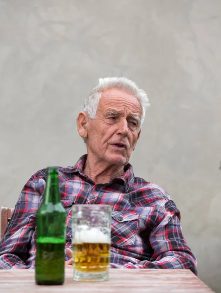 Starszy człowiek z butelki piwa i kubek — Zdjęcie stockowe