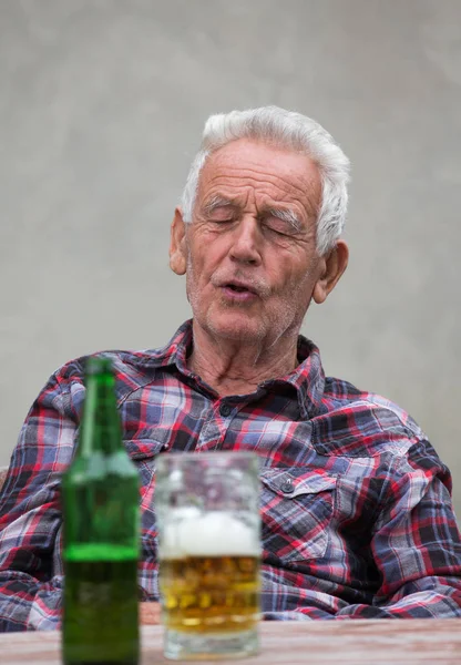 Hombre mayor con botella de cerveza y taza — Foto de Stock