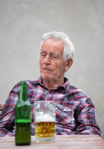 Homme âgé avec bouteille de bière et tasse — Photo