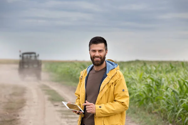 Farmer tenant tablette avec tracteur derrière — Photo