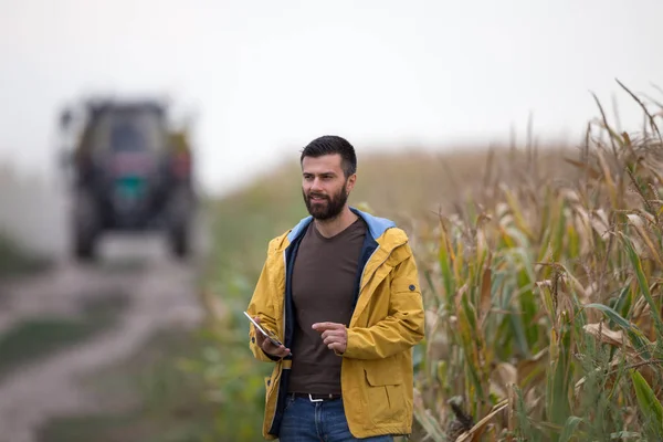 Landwirt hält Tablet mit Traktor hinter sich — Stockfoto