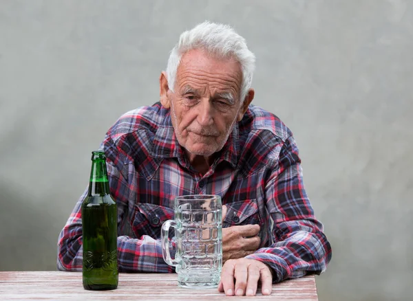 Sênior com garrafa de cerveja e caneca — Fotografia de Stock