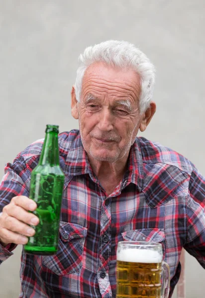 Hombre mayor con botella de cerveza y taza — Foto de Stock