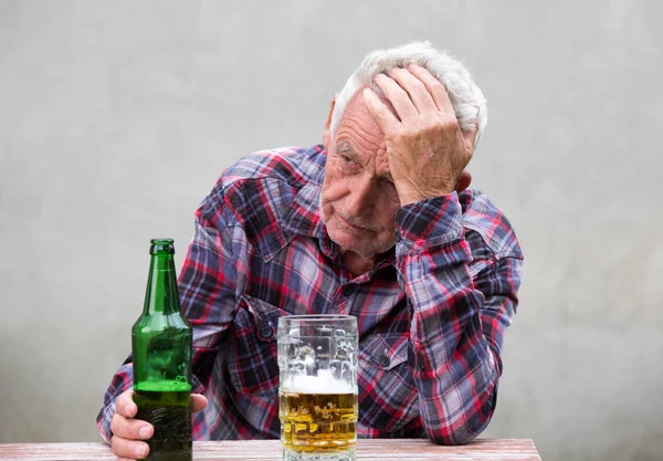 Uomo anziano con bottiglia di birra e tazza — Foto Stock