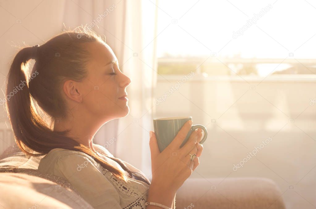 Girl smelling coffee on sunshine