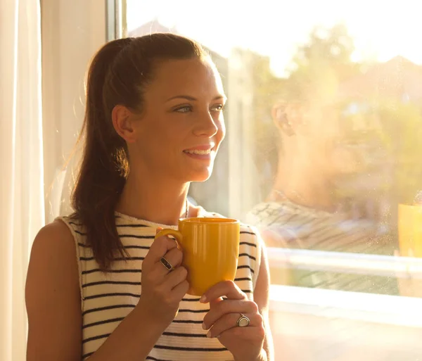 Flicka med kaffe bredvid fönster — Stockfoto