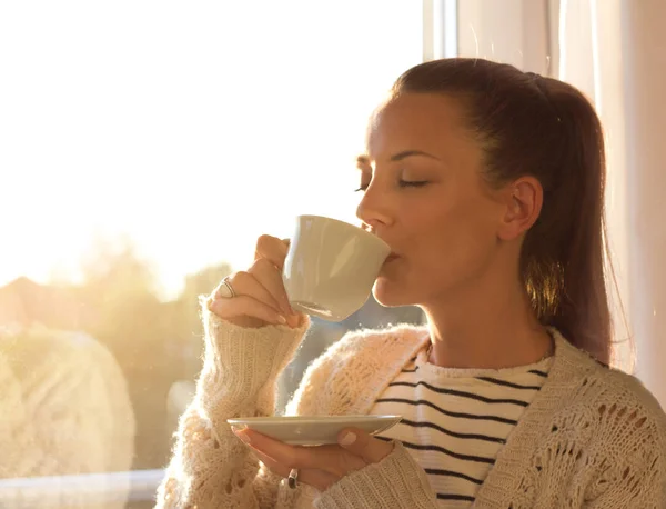 Flicka med kaffe bredvid fönster — Stockfoto