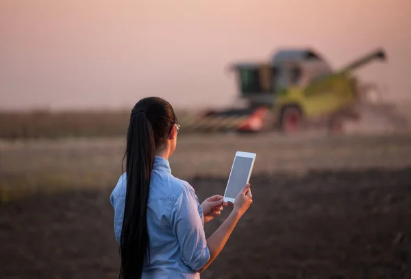 Menina agricultor com tablet e colheitadeira — Fotografia de Stock