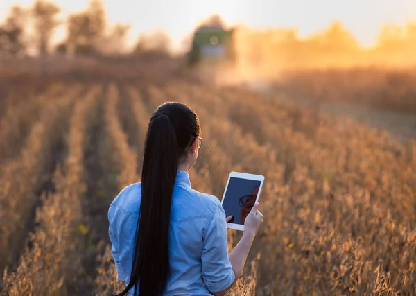 Chica agricultora con tableta y cosechadora — Foto de Stock
