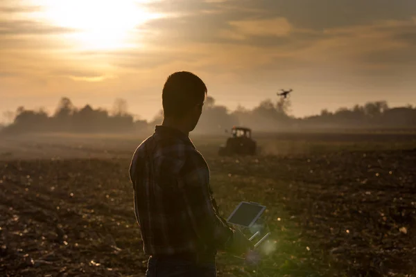 Petani menavigasi drone di atas tanah pertanian — Stok Foto