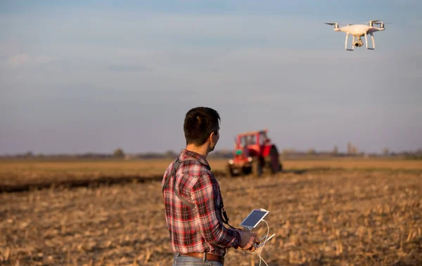 Petani menavigasi drone di atas tanah pertanian — Stok Foto