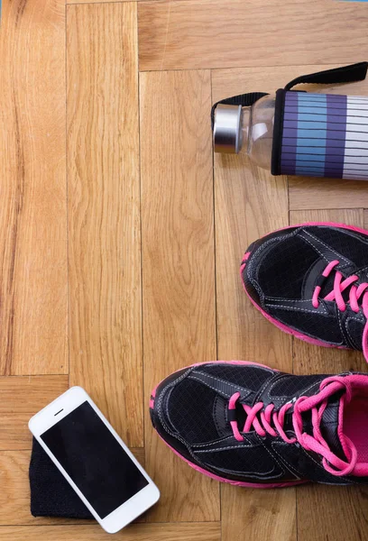 Zapatos deportivos con botella y teléfono en el suelo — Foto de Stock