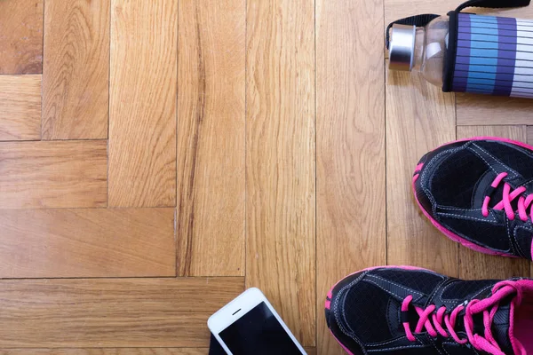 Zapatos deportivos con botella y teléfono en el suelo — Foto de Stock