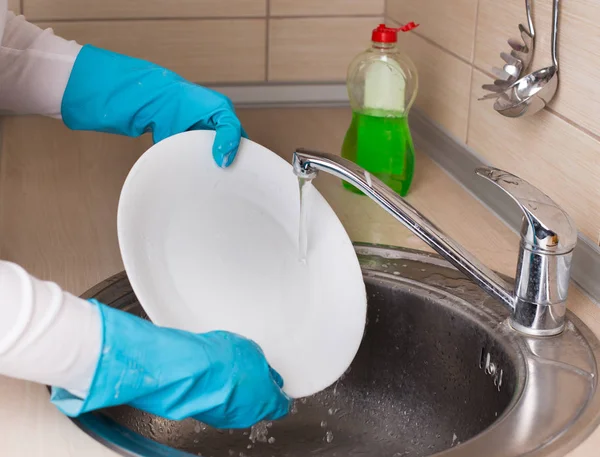 Женщина моет посуду в раковине — стоковое фото