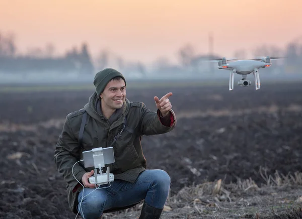 Farmer navigating drone above farmland