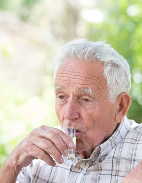 Old man drinking short drink — Stock Photo, Image