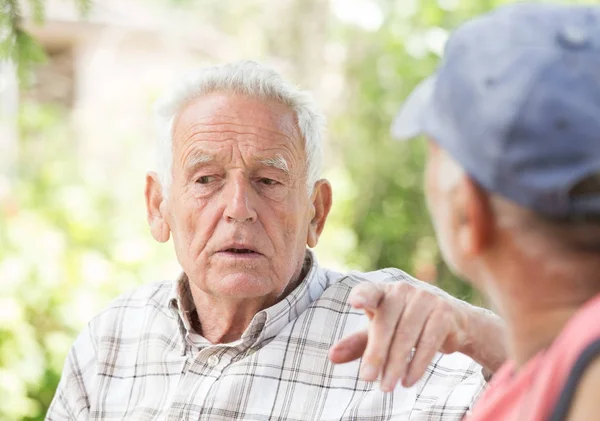 Двое старших мужчин разговаривают в парке — стоковое фото