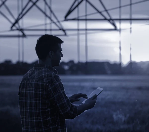 Agricultor com tablet na frente do sistema de irrigação — Fotografia de Stock