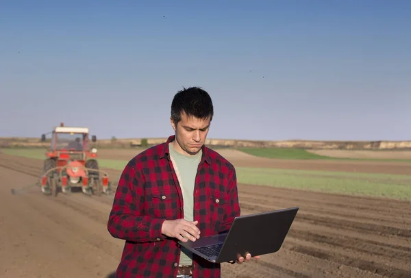 Agricoltore con computer portatile e trattore semina — Foto Stock