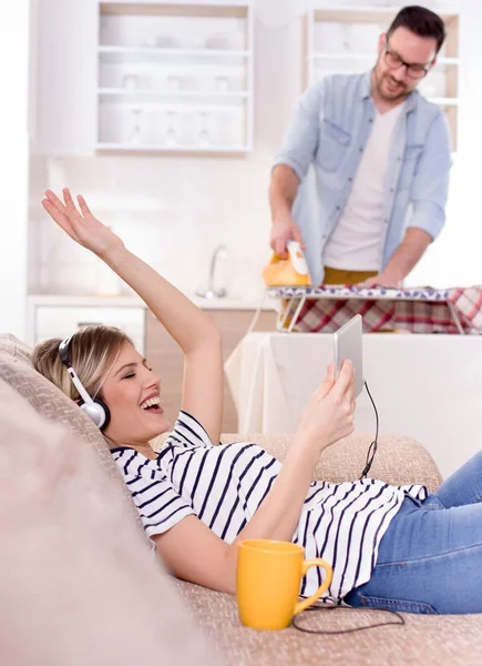 Homem engomando enquanto mulher descansando — Fotografia de Stock