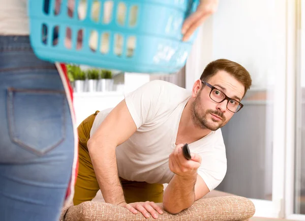 Vrouw doen klusjes terwijl man tv kijken — Stockfoto