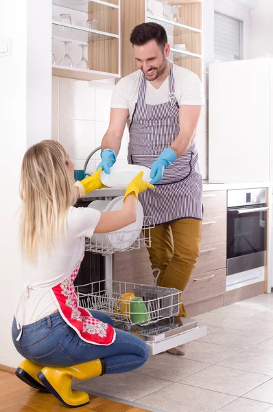 Счастливая пара разгружает посудомоечную машину — стоковое фото