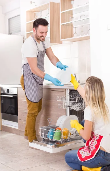 Glückliches Paar lädt Geschirrspüler aus — Stockfoto