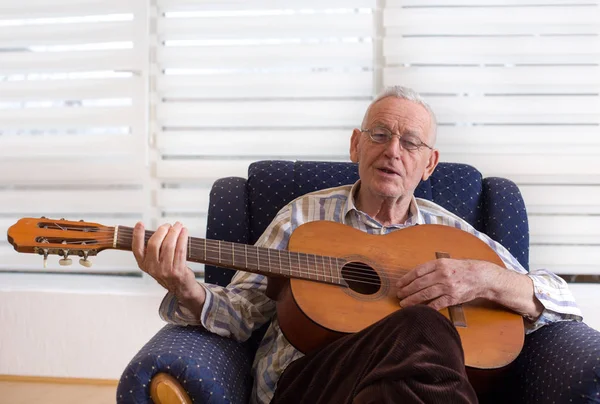 Старик играет на гитаре дома — стоковое фото