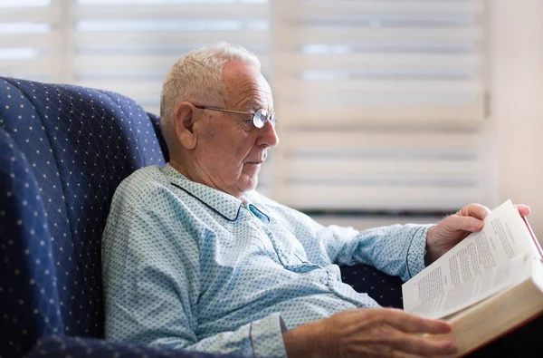 Старик читает книгу дома — стоковое фото