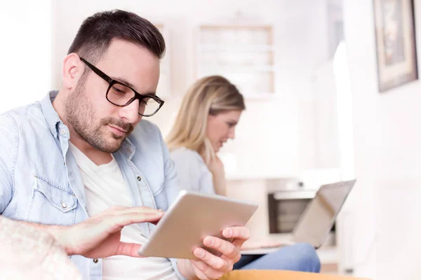 Homem e mulher olhando para tablet e laptop — Fotografia de Stock