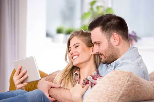 Casal jovem olhando para tablet e rindo de casa — Fotografia de Stock