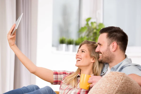 Casal jovem olhando para tablet e rindo de casa — Fotografia de Stock