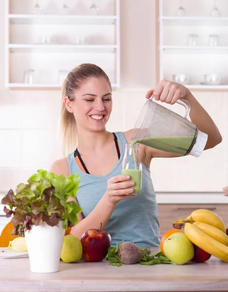 Menina derramando smoothie em garrafa na cozinha — Fotografia de Stock