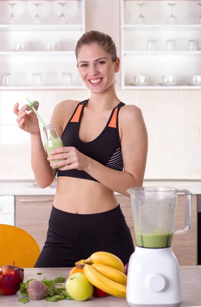 Girl holding bottle with green smoothie in kitchen — Stock Photo, Image
