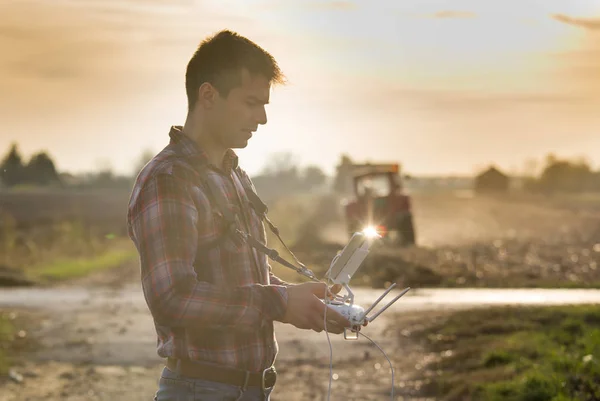 Agricultor navegando dron sobre tierras de cultivo — Foto de Stock