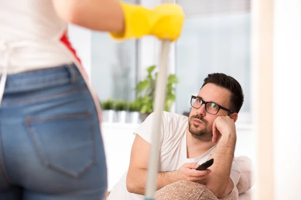 Mujer fregando piso mientras hombre viendo tv —  Fotos de Stock