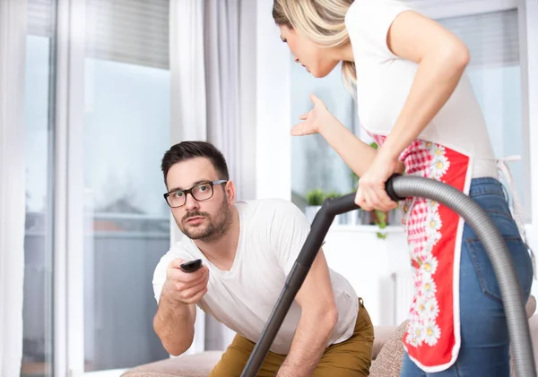 Woman vacuuming while man watching tv — Stock Photo, Image