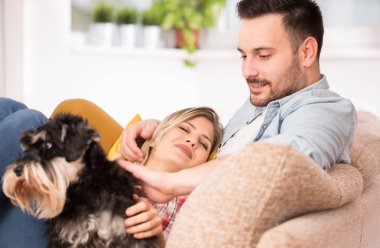 Genç çift koltuk üzerinde köpek zevk ile sarılmak,