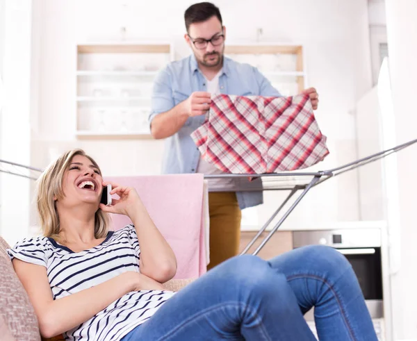 Kobieta rozmawia z telefonu, gdy człowiek robi prace domowe — Zdjęcie stockowe
