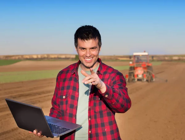 Удовлетворенный фермер ноутбуком и трактором — стоковое фото