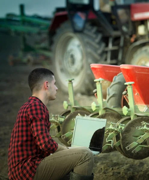 Fermier avec ordinateur portable et tracteurs — Photo