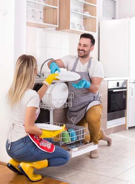 Casal feliz descarregando máquina de lavar louça — Fotografia de Stock